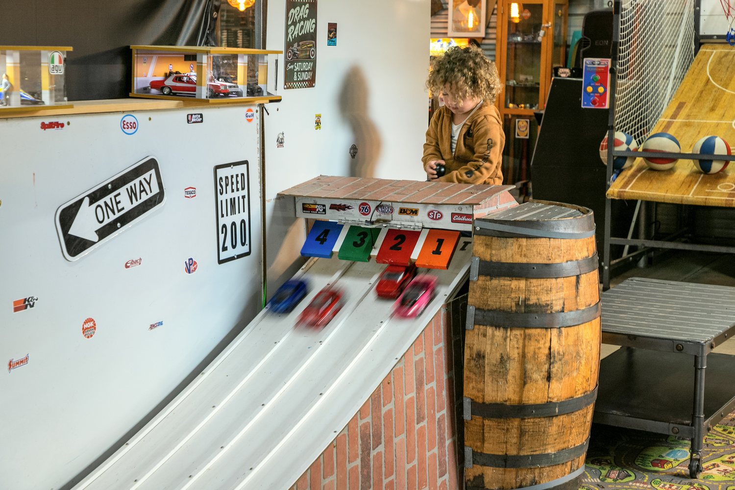 A toddler releasing cars down the four-lane pinewood derby track.
